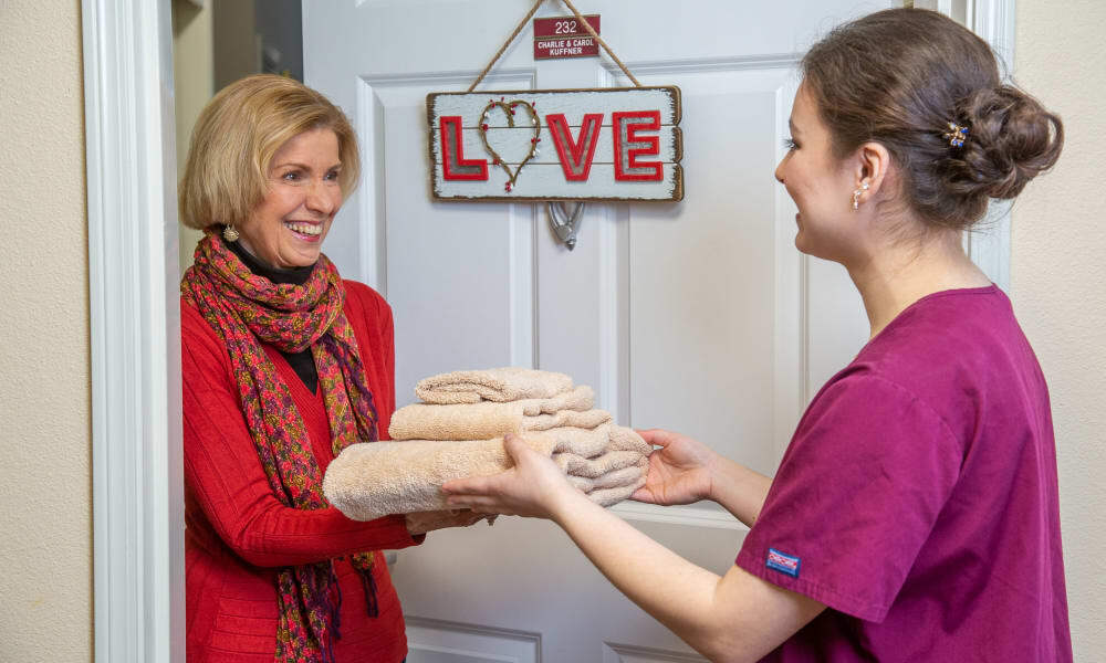 A team member delivering fresh linens to a resident at Steeplechase